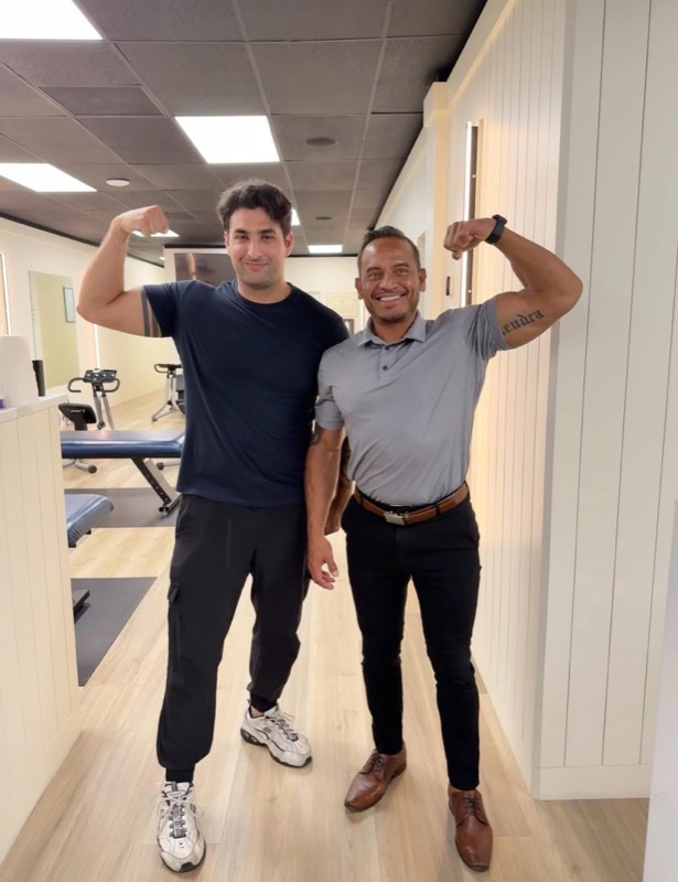 Dr. Steve flexing with a smiling patient in the treatment area